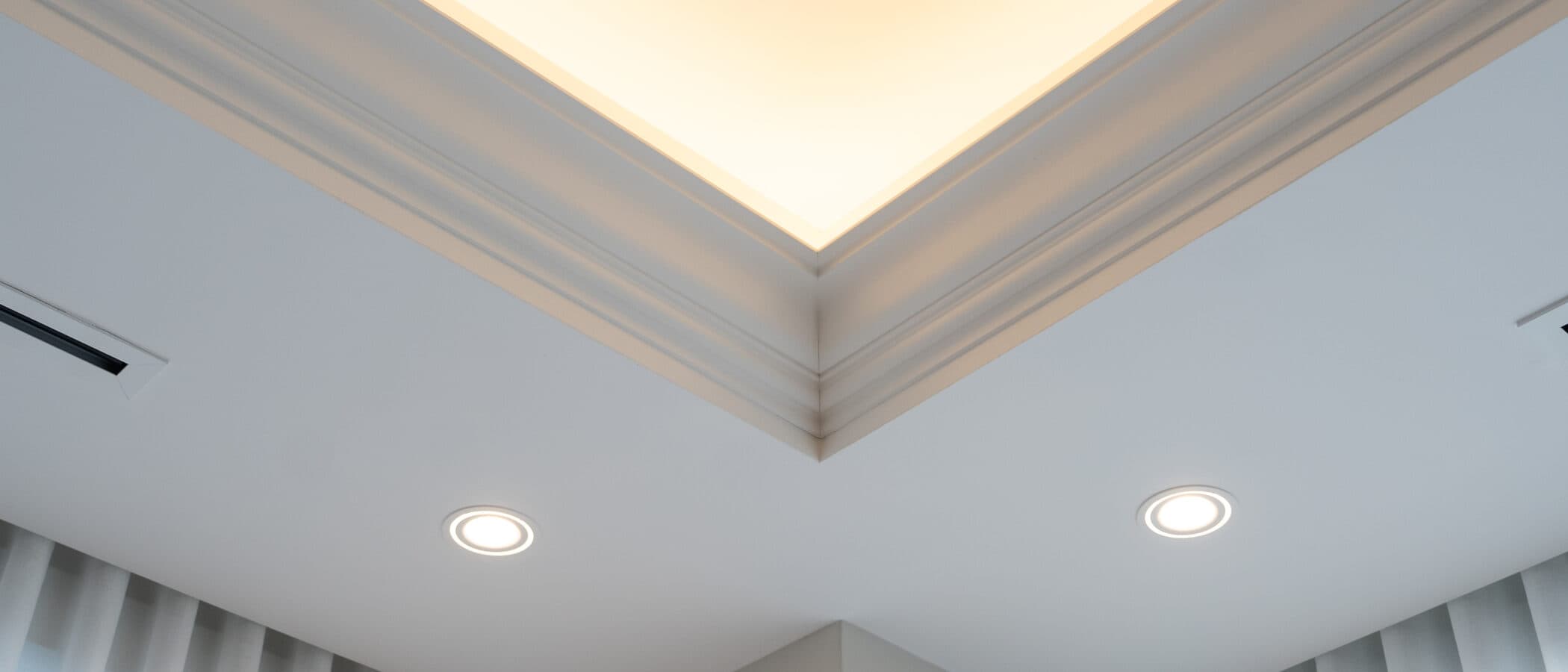 Cove lit ceiling corner above sheer drapery