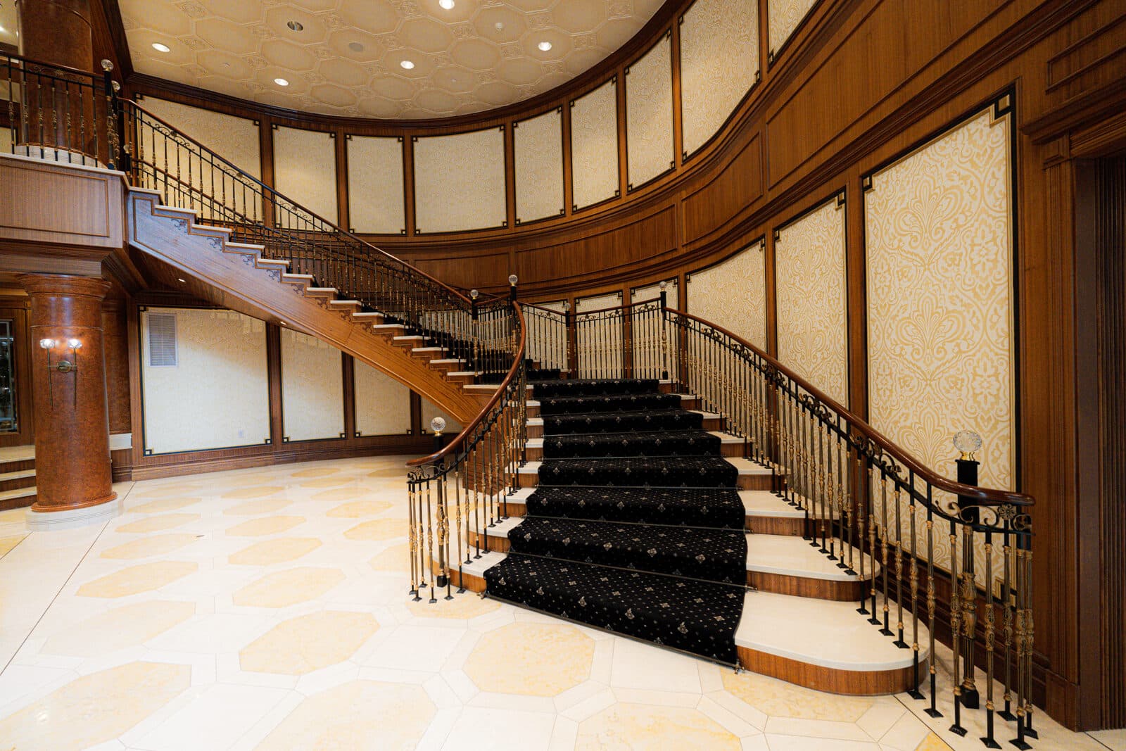 Sweeping mahogany staircase with a patterned black runner in the Avignon lobby