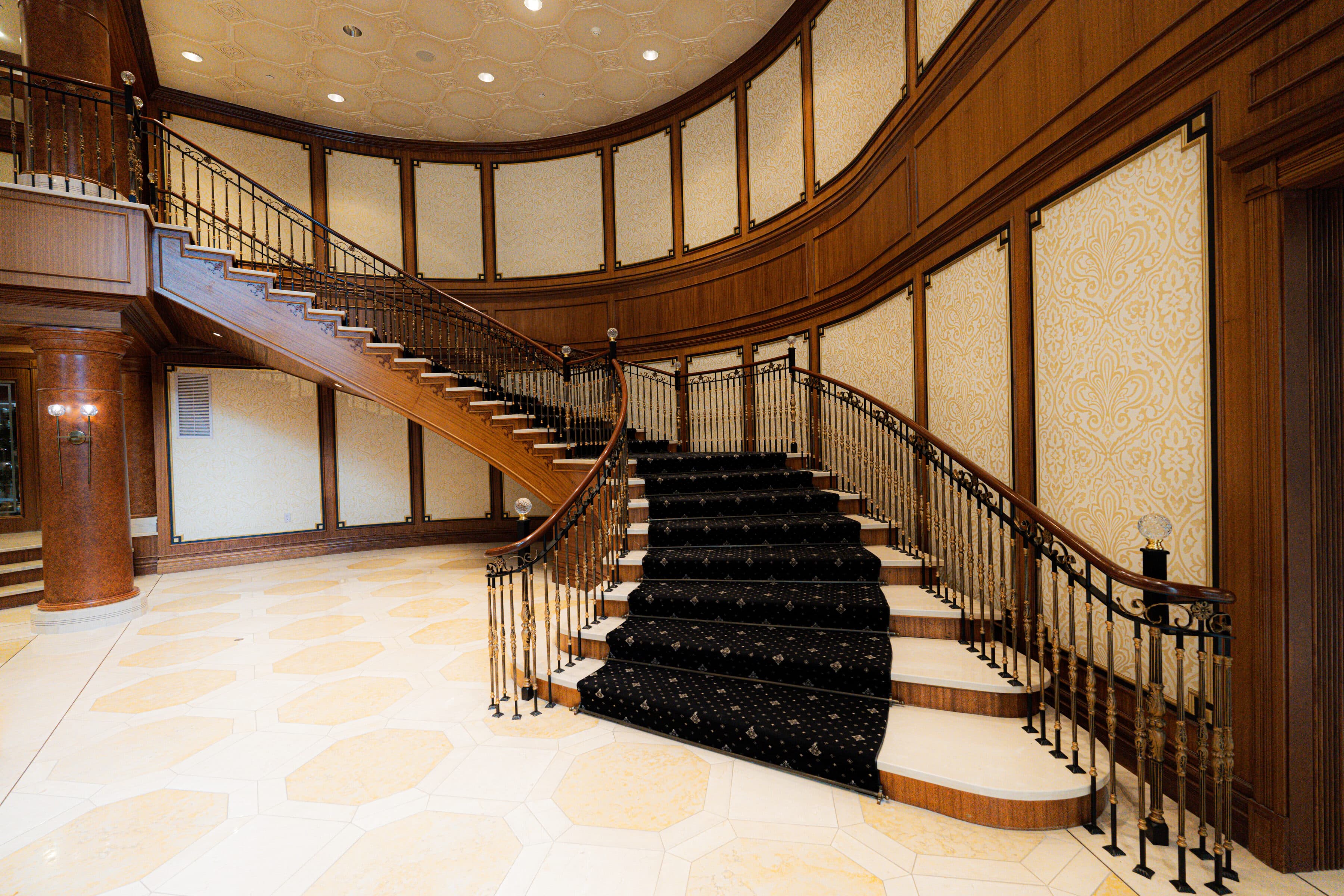 Sweeping mahogany staircase with a patterned black runner in the Avignon lobby