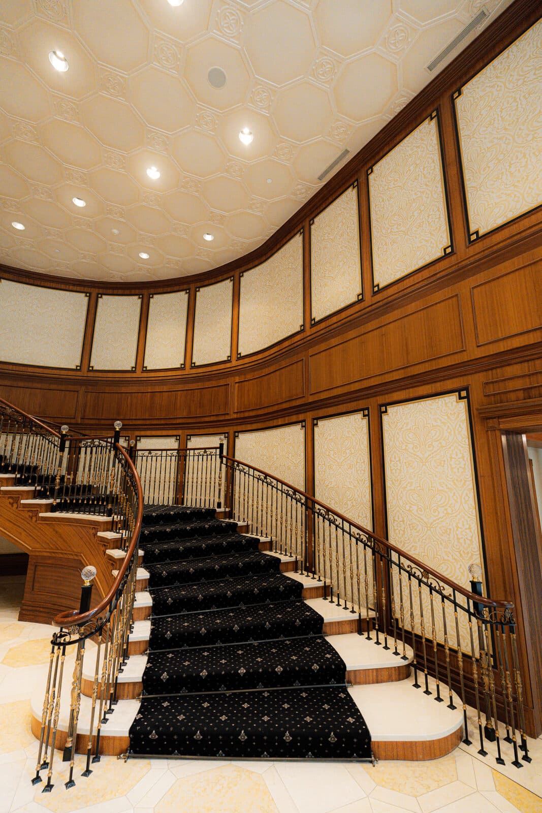 Straight on view up the stair runner between iron balustrades