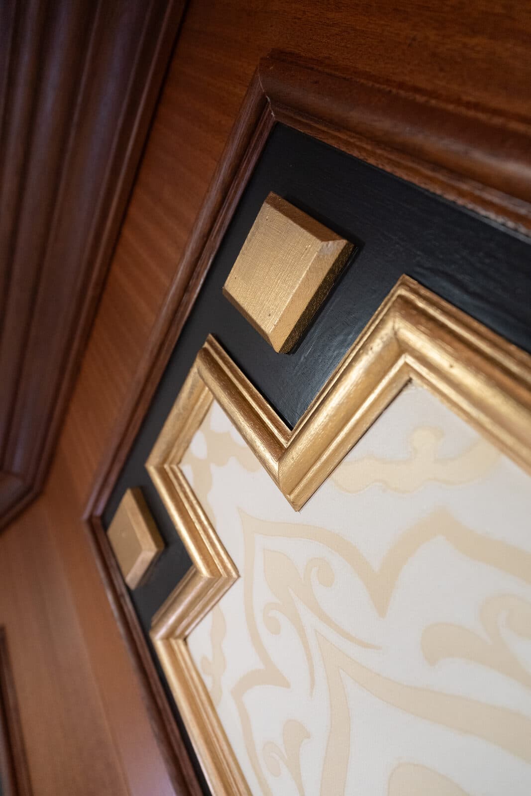 Gilt corner detail where mahogany trim meets black lacquer