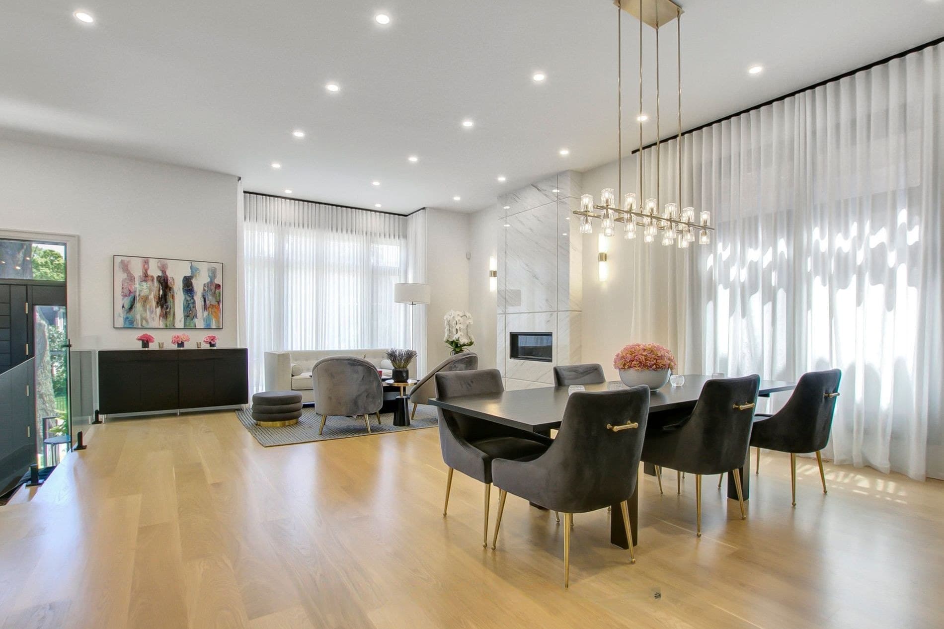 Open living and dining space with a slab marble fireplace and a linear brass chandelier