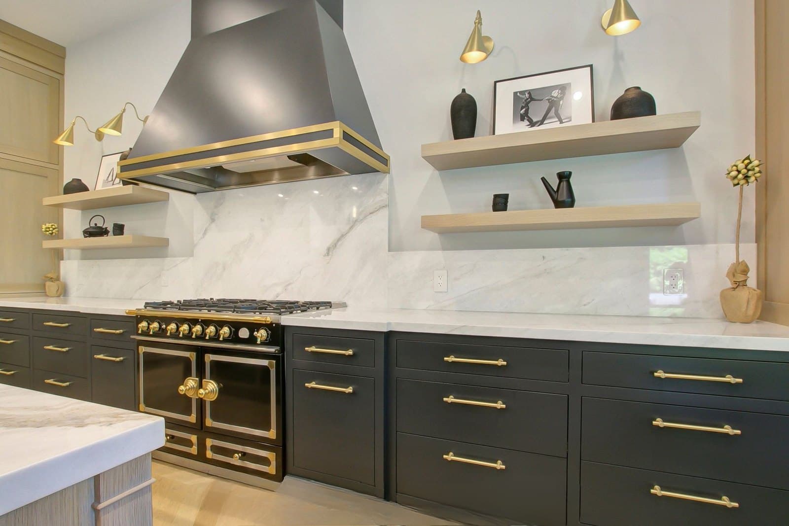 Chef kitchen in charcoal cabinetry with a brass range and marble surfaces