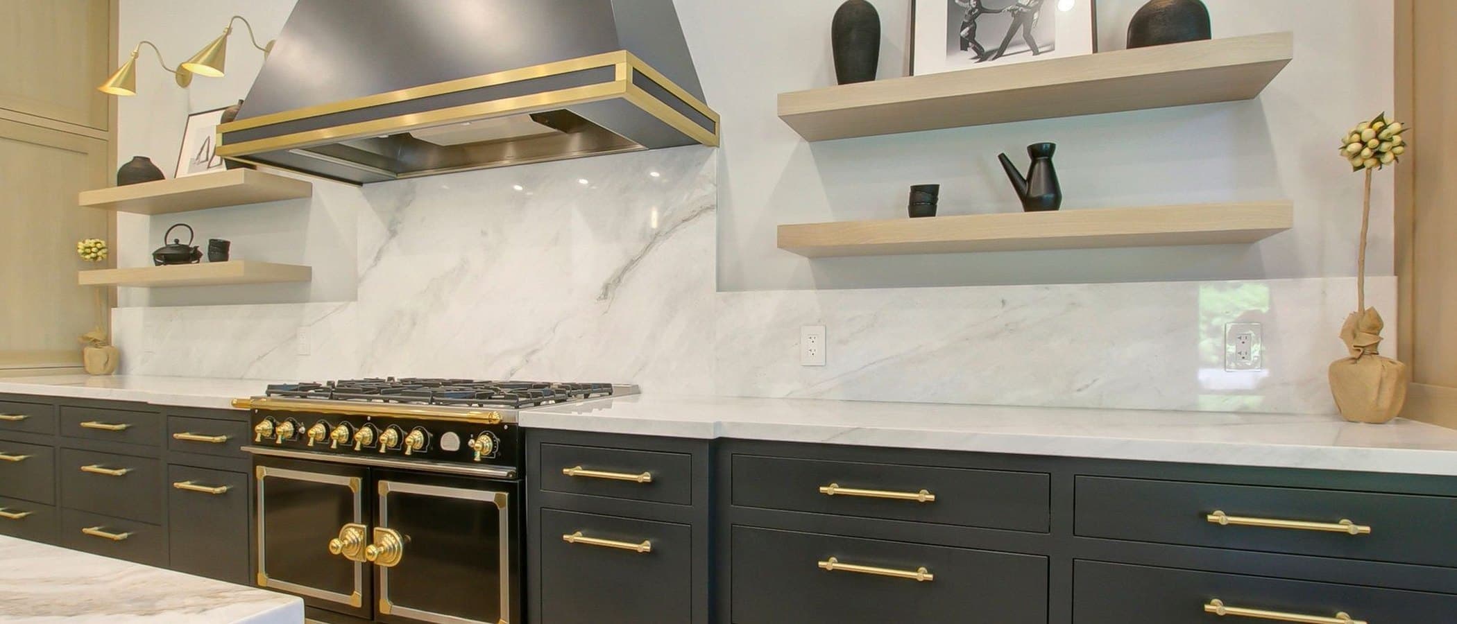 Chef kitchen in charcoal cabinetry with a brass range and marble surfaces