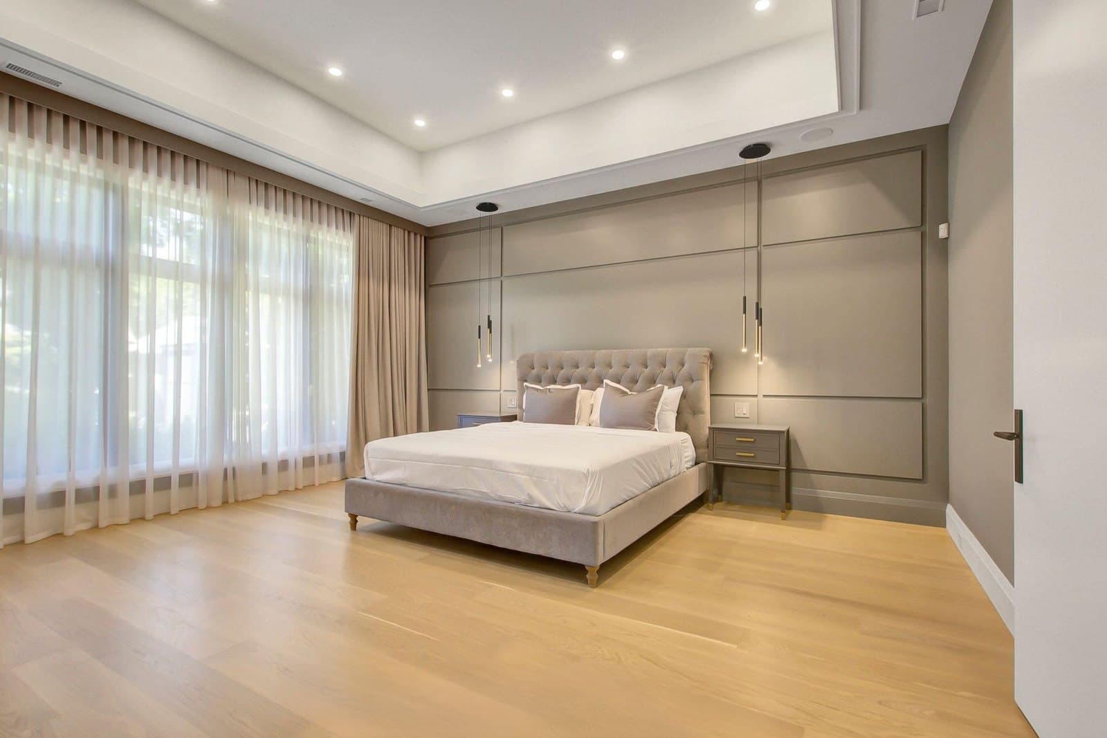 Principal bedroom with a panelled feature wall and soft layered drapery