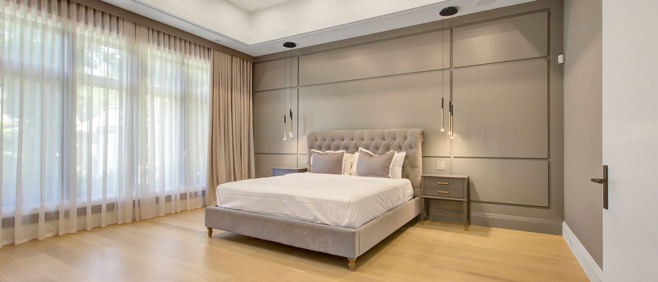 Principal bedroom with a panelled feature wall and soft layered drapery