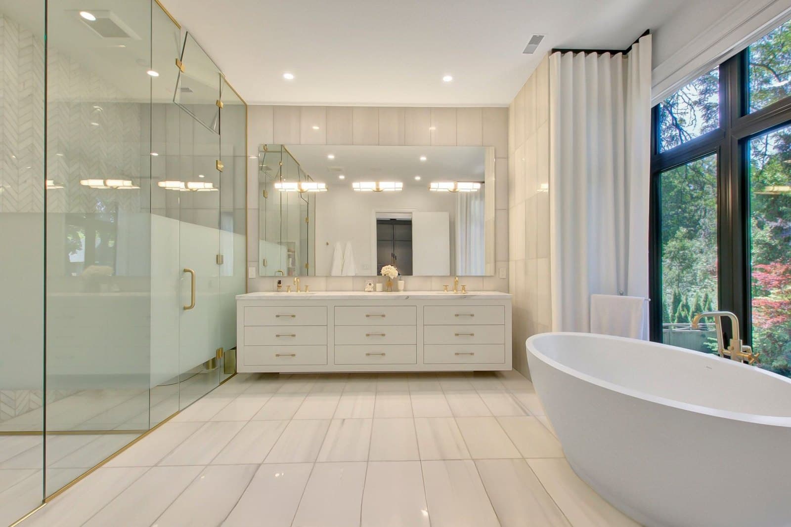 Principal bathroom with a freestanding tub and a glass walled shower in pale stone
