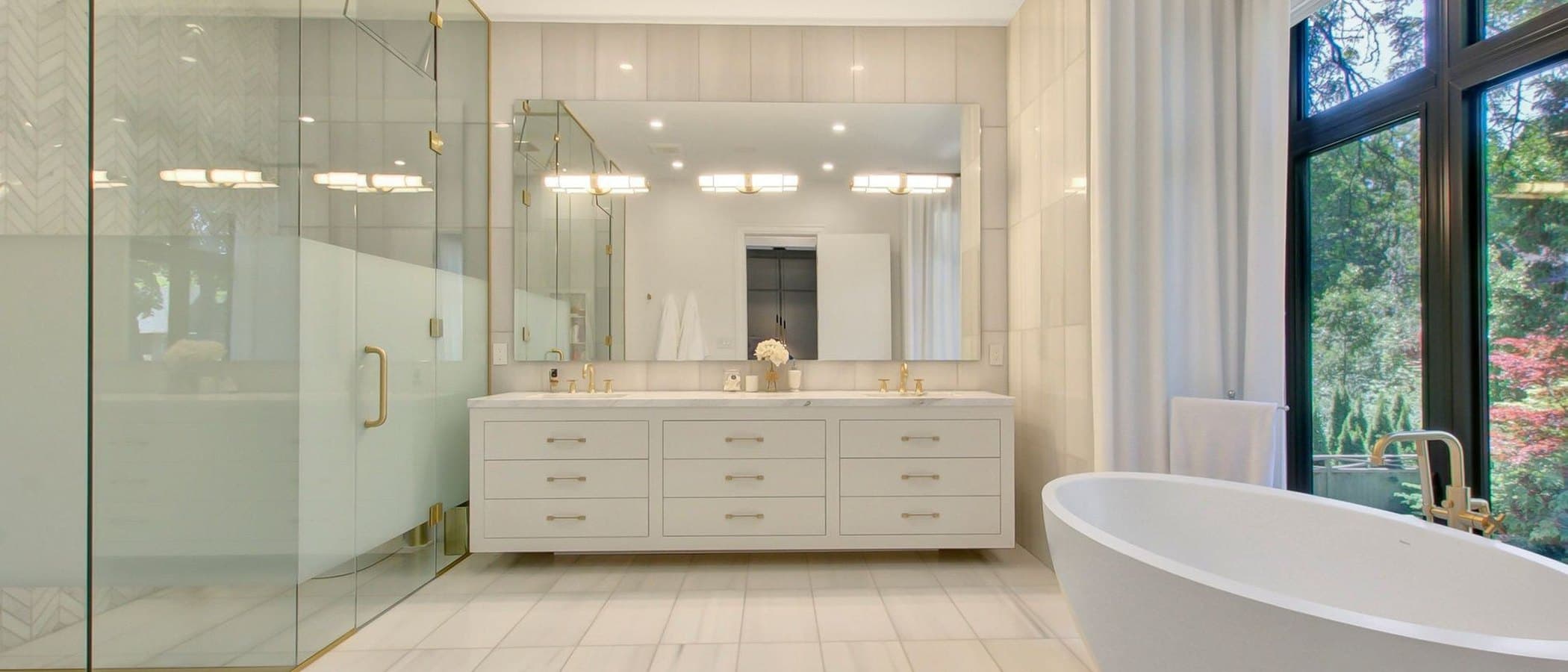 Principal bathroom with a freestanding tub and a glass walled shower in pale stone