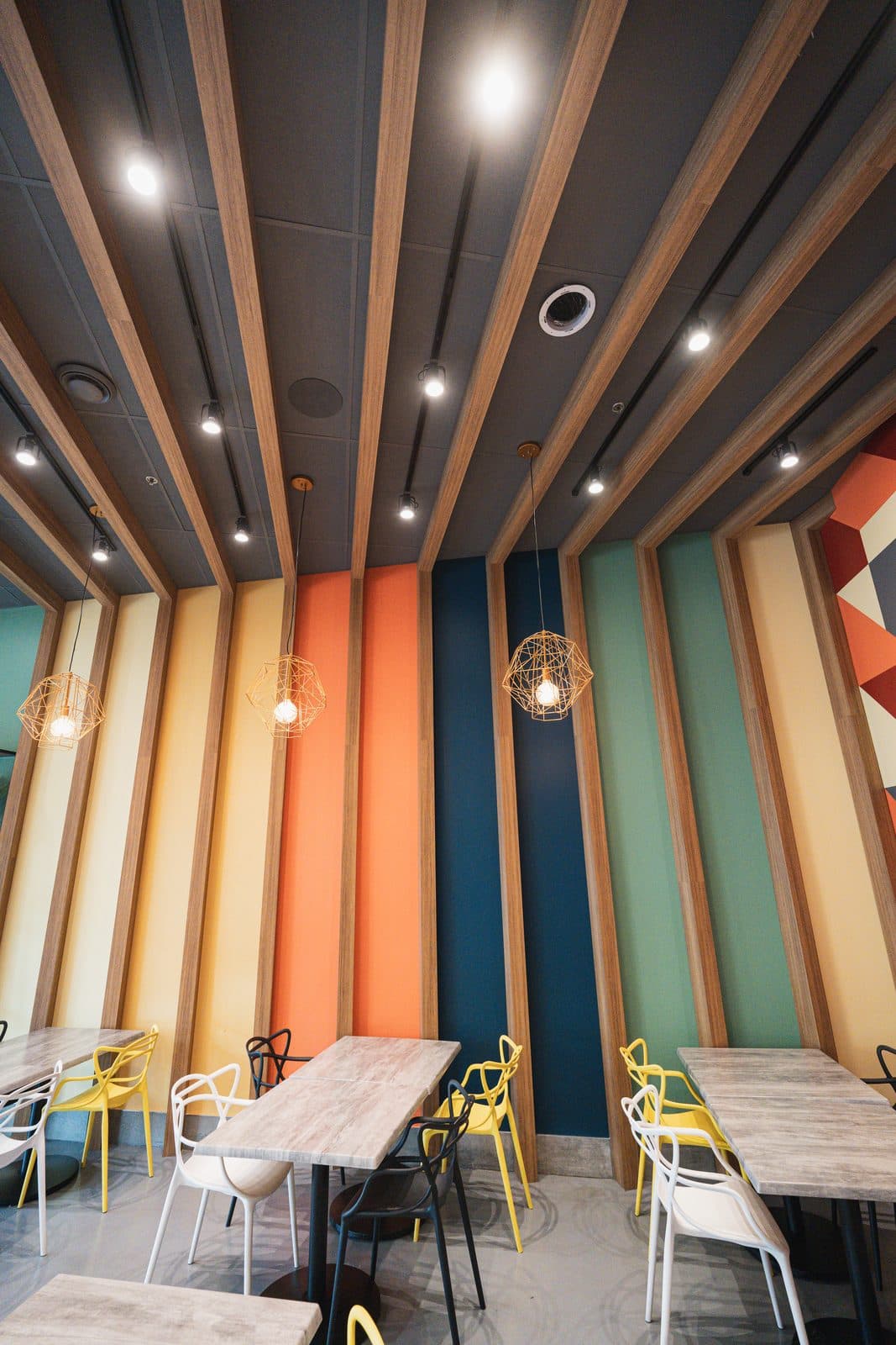 Coloured wall panels with wire pendants above the tables