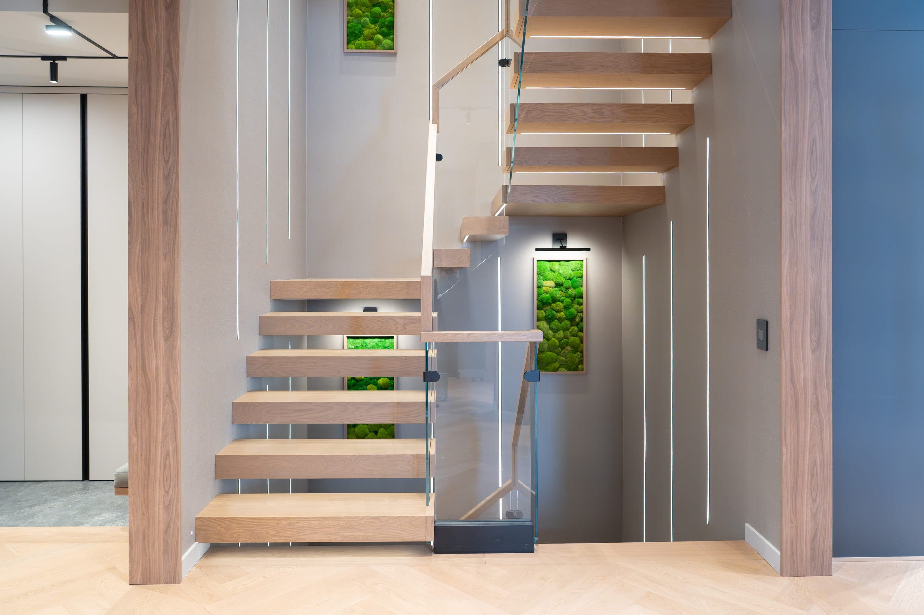 Floating oak stair with backlit moss panels and concealed lighting at the entry
