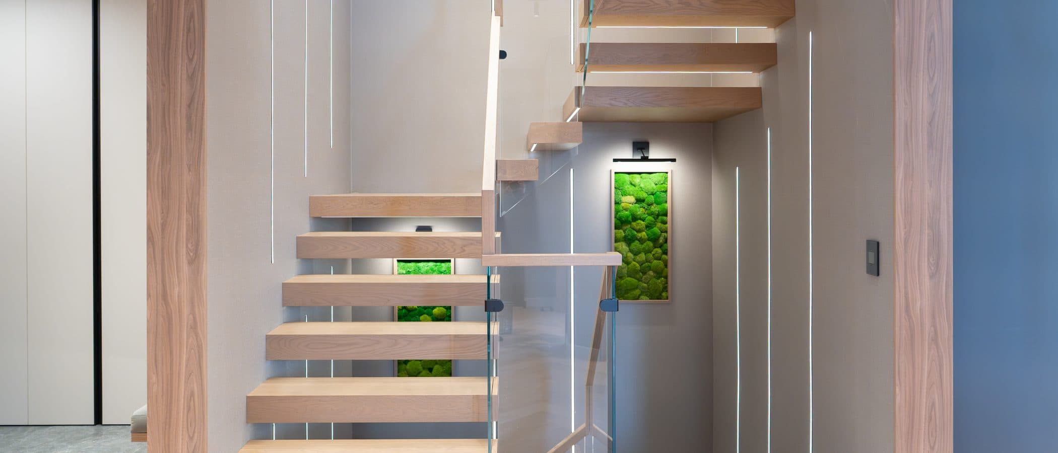 Floating oak stair with backlit moss panels and concealed lighting in a finished Leman custom home