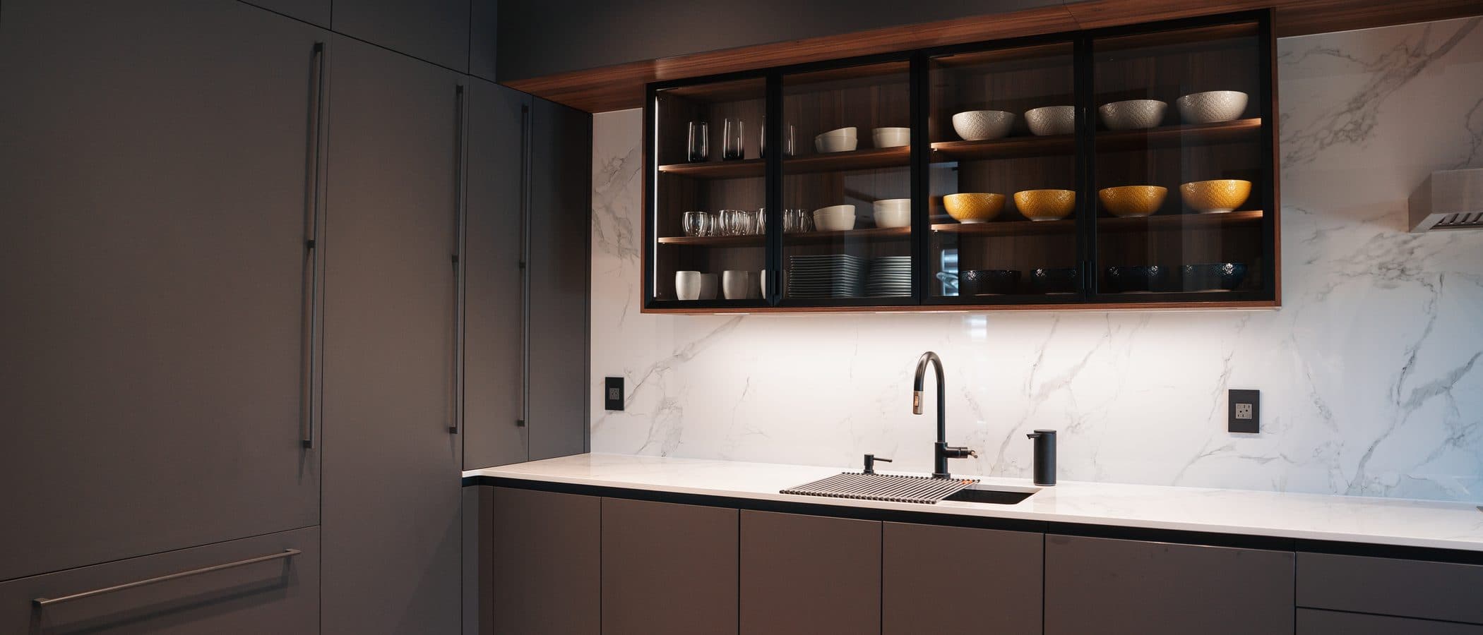 Charcoal kitchen with backlit glass cabinets and a marble backsplash