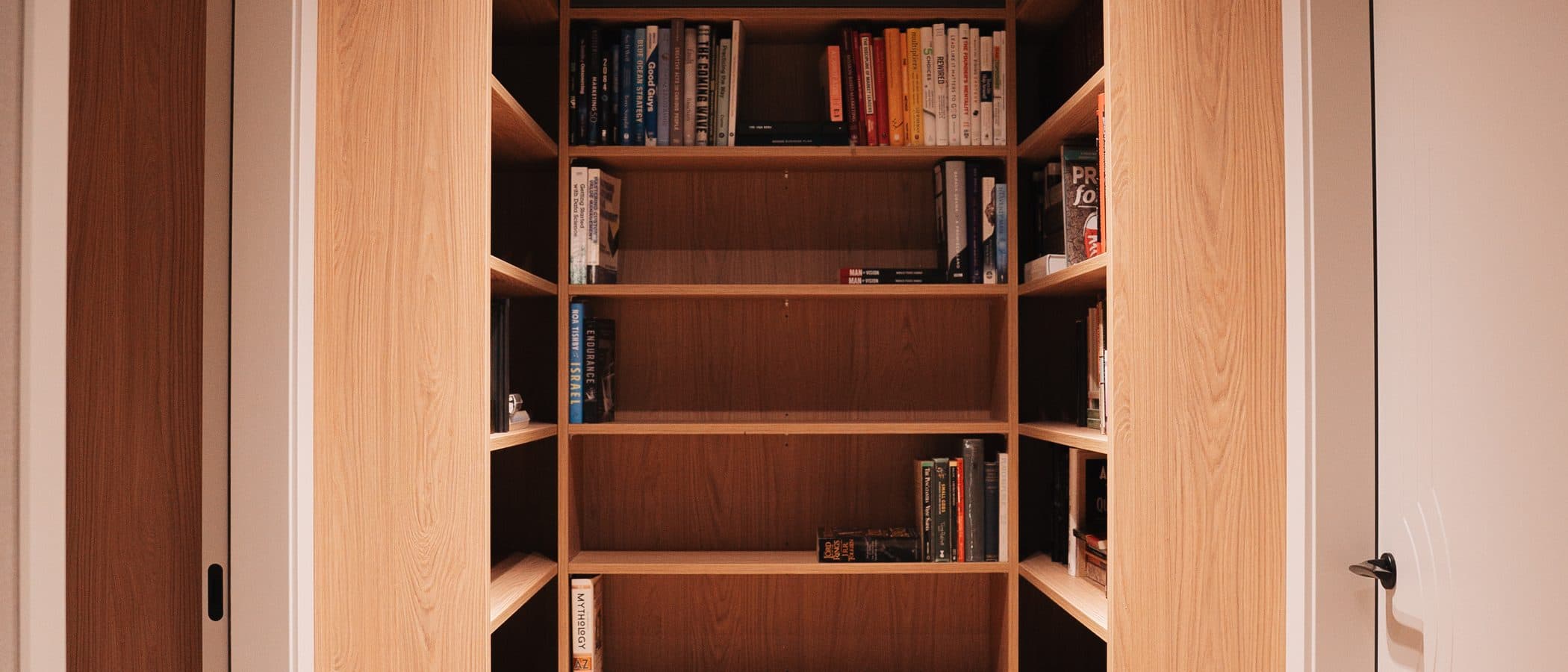Walnut library corridor with backlit shelving and oak floors