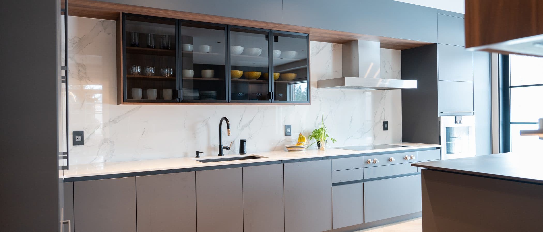 Charcoal kitchen along a marble backsplash with an integrated hood and island