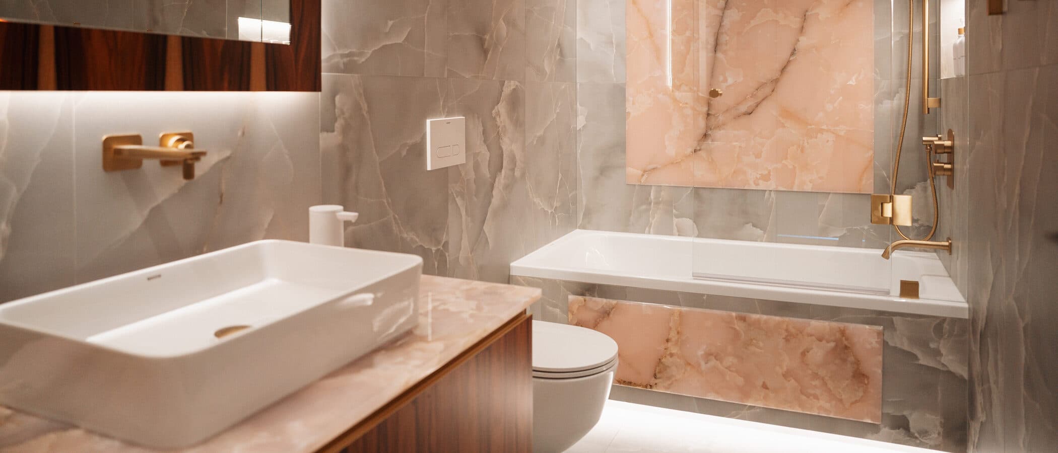 Pink onyx bathroom with a layered vanity, backlit mirror and freestanding tub