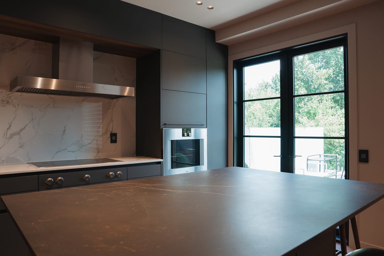 Kitchen with a stone island opening toward a glazed walkout