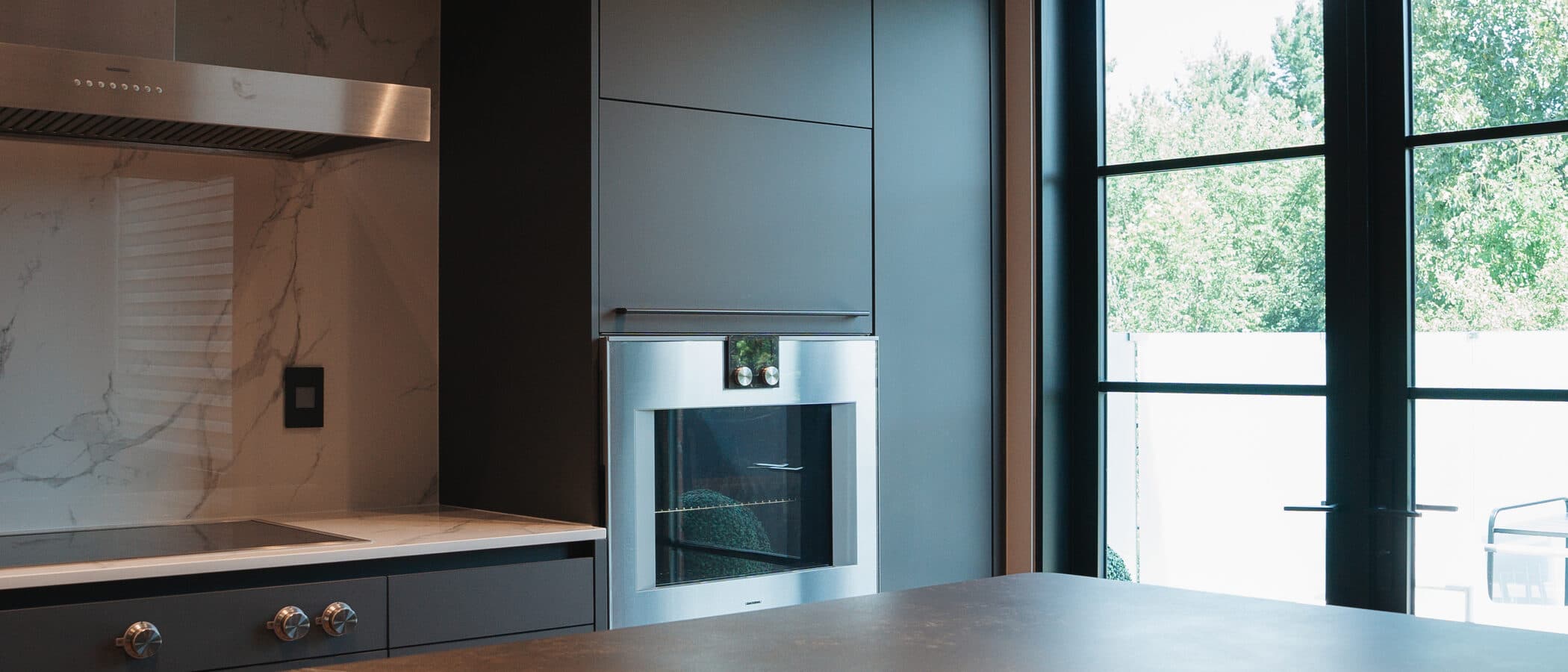 Kitchen with a stone island opening toward a glazed walkout
