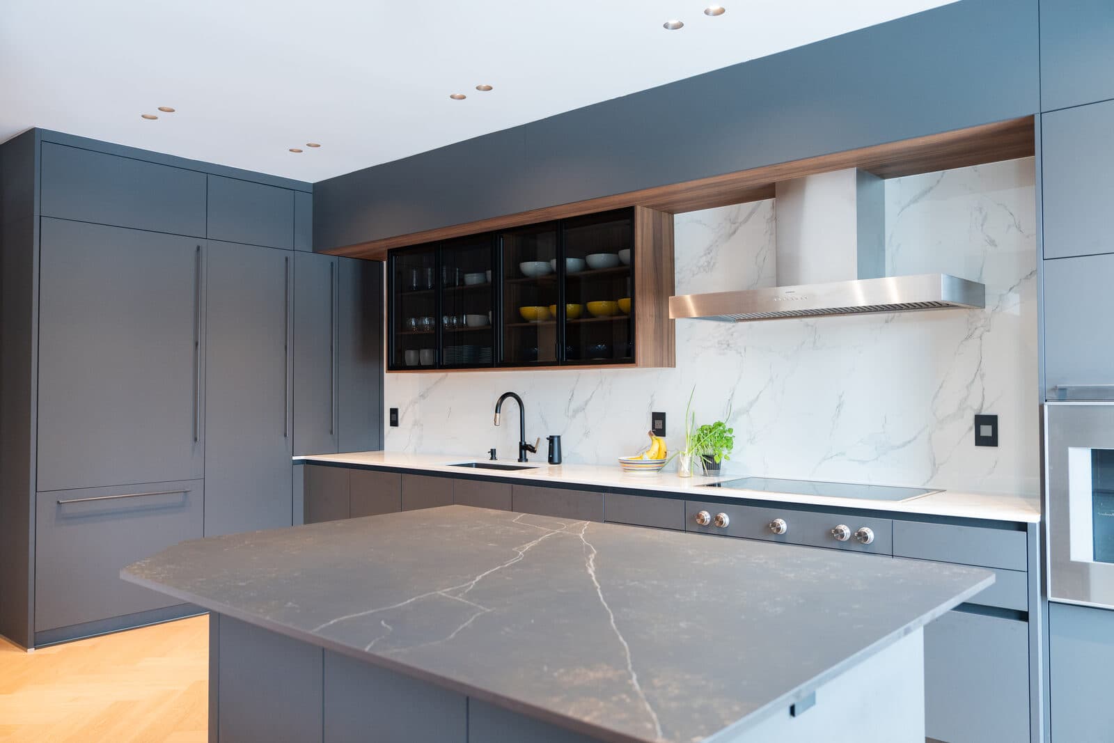 Kitchen with a marble backsplash and a backlit glass shelf display