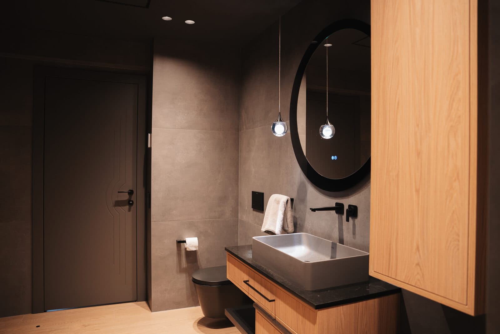 Grey powder room with a round mirror and a glass drop pendant