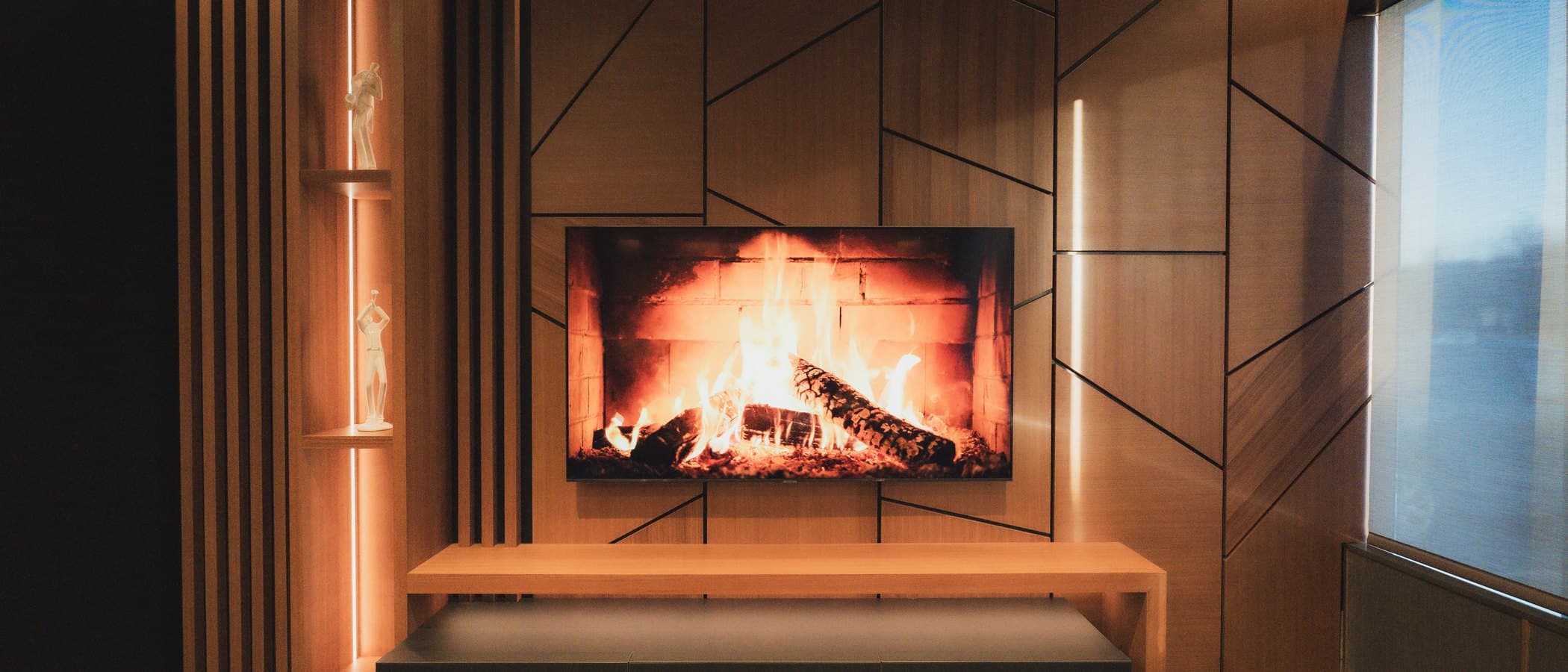Lounge with a linear fireplace set into a wood panelled wall at the Leman showroom