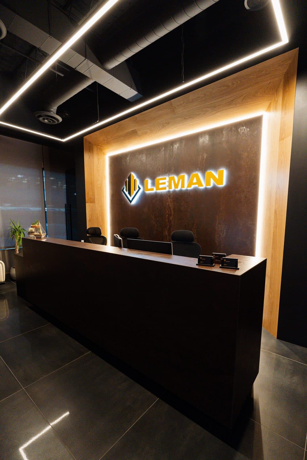 Reception area beneath the illuminated studio sign in dark tones with brass accents