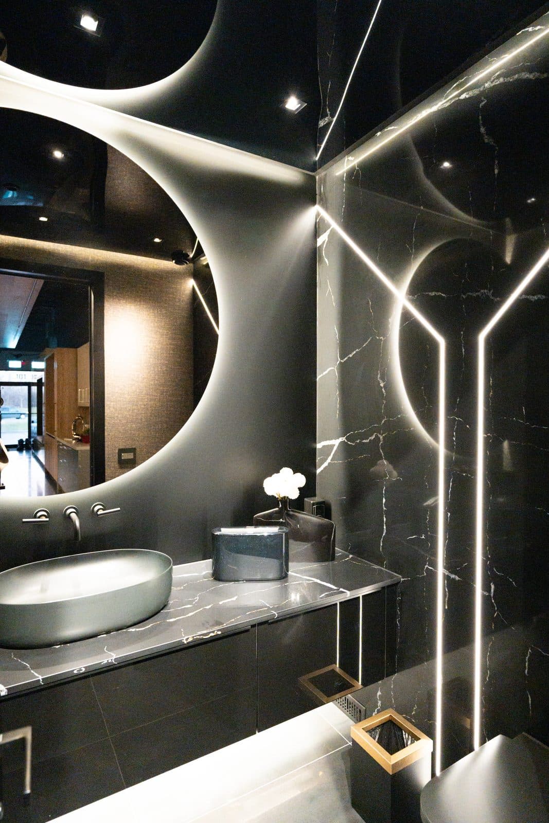 Powder room with a circular halo of light framing a stone vessel sink