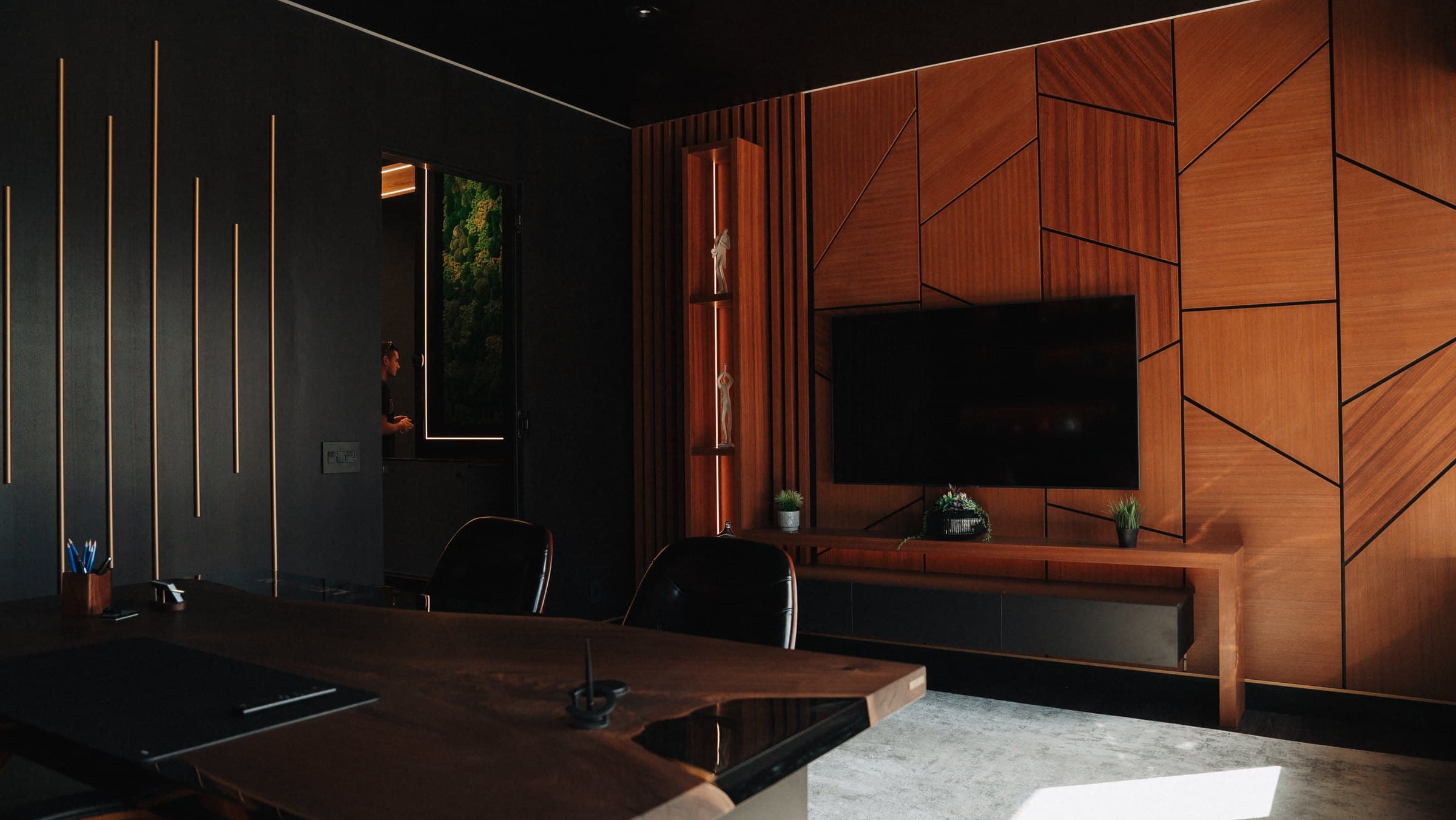 Private office with a geometric wood feature wall and integrated display shelving
