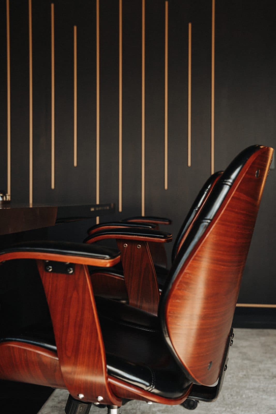 Walnut framed leather chair beside a backlit slat wall in the studio