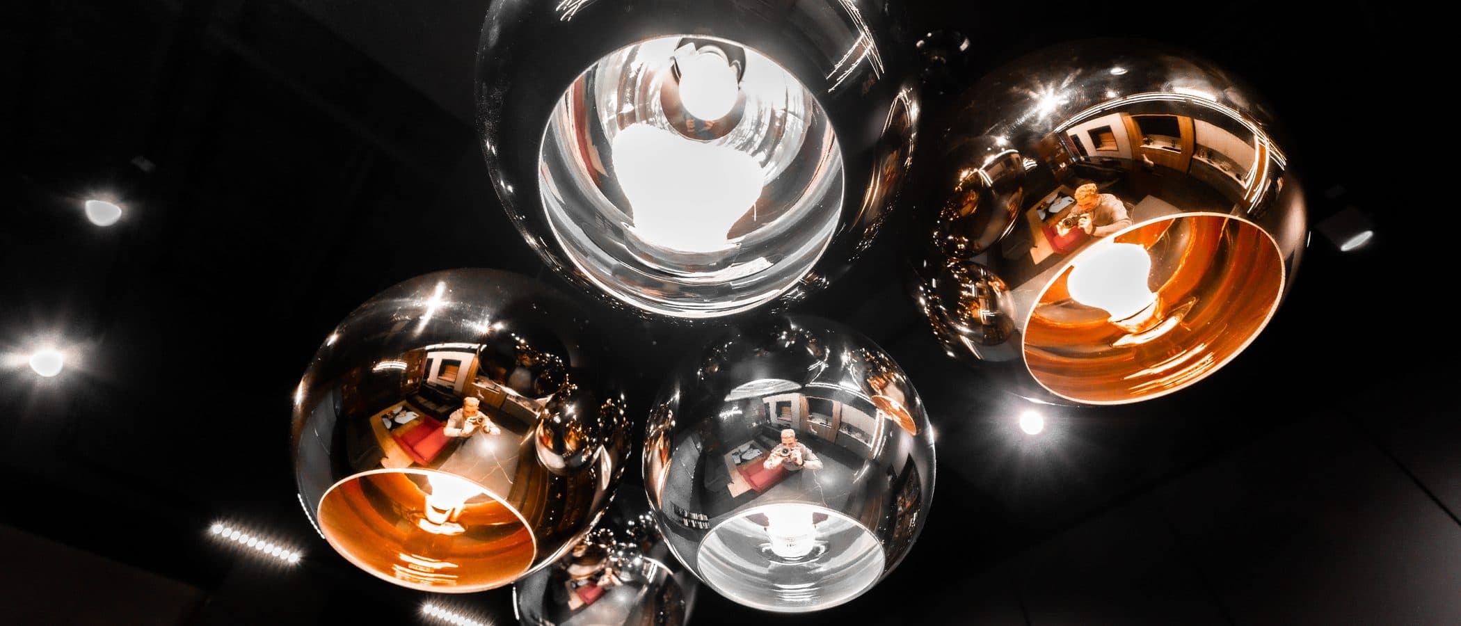 Cluster of mirrored globe pendant lights photographed from below, reflecting the studio interior