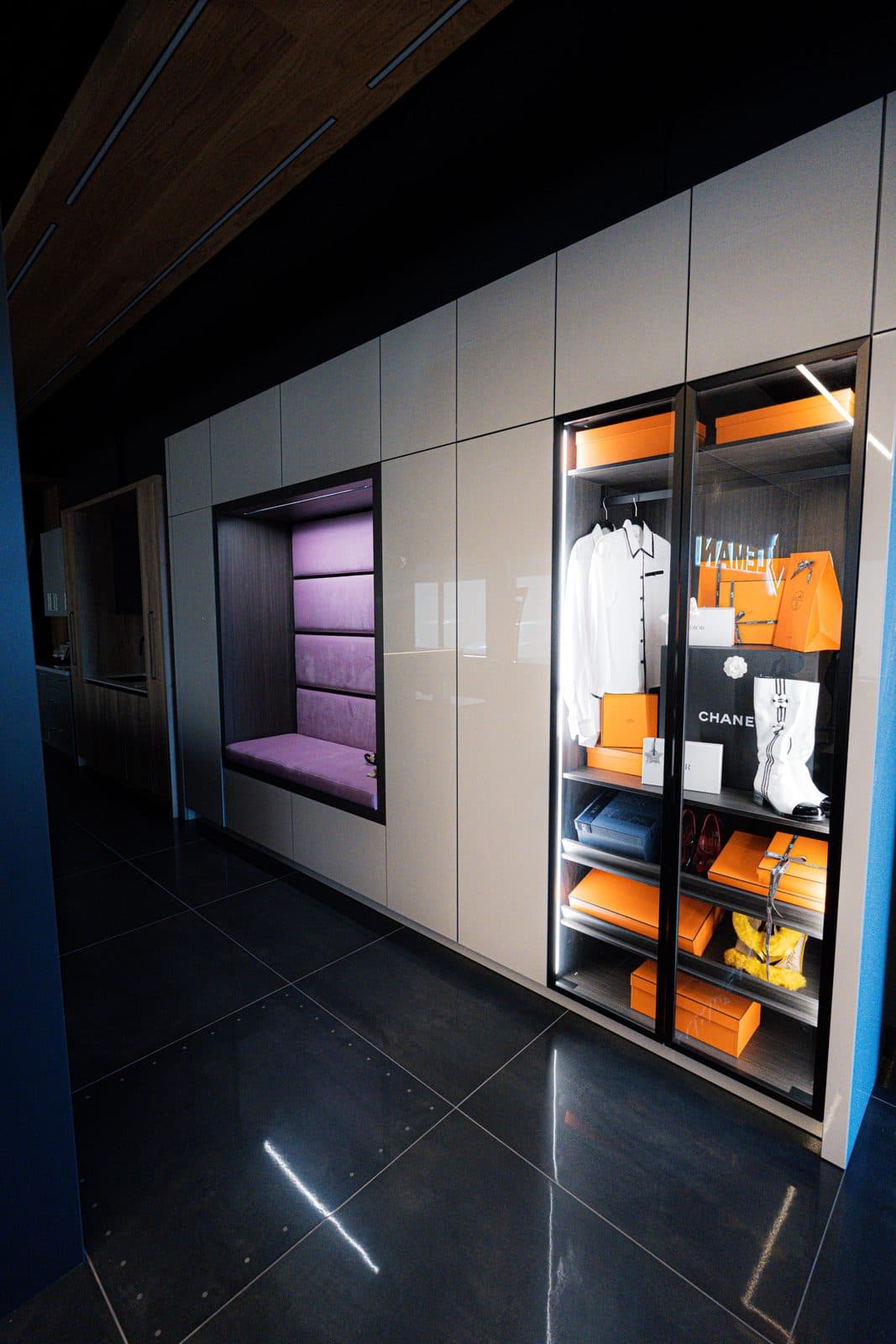 Boutique display closet with a velvet bench and a lit cabinet of designer accessories