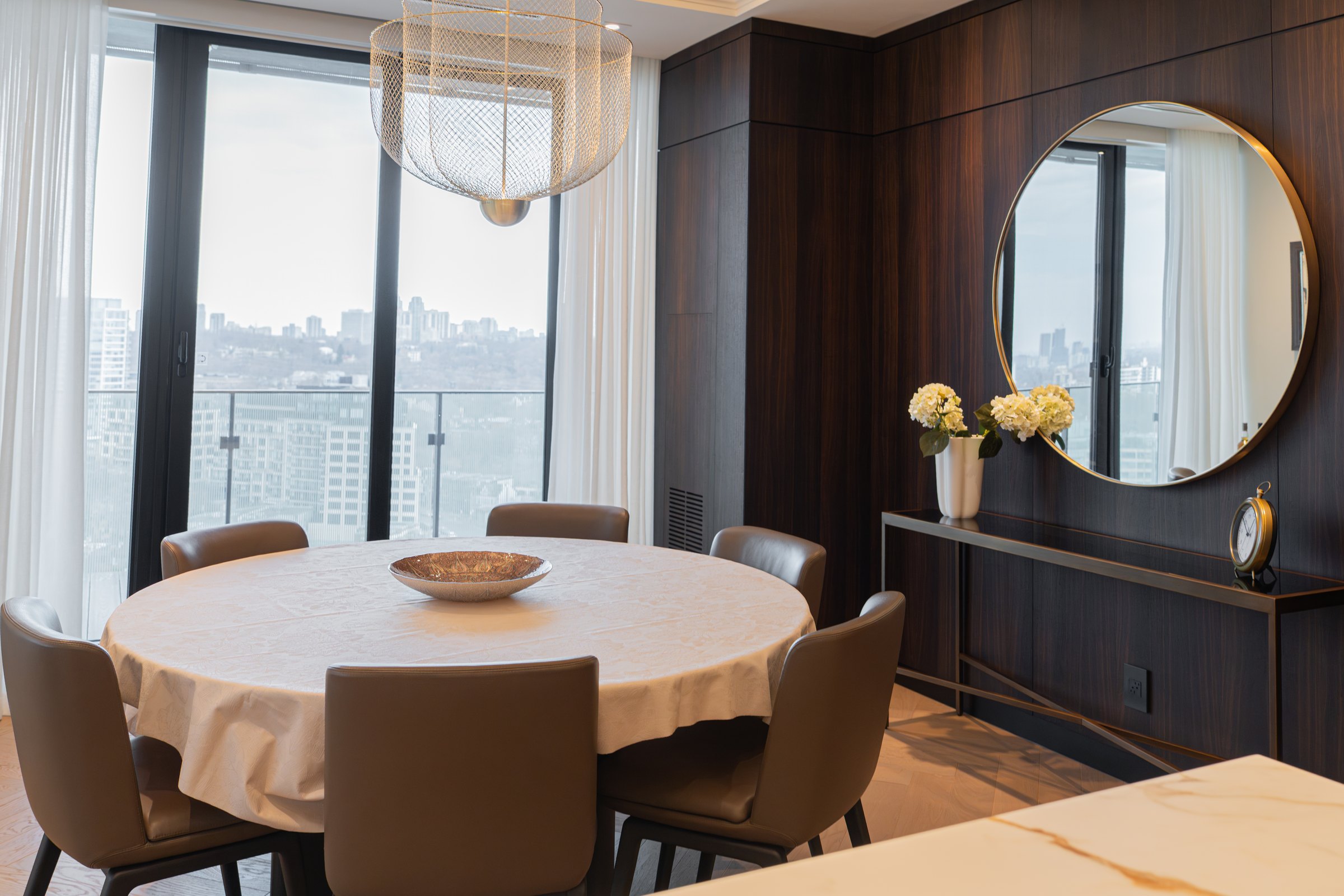 Dining room in walnut panelling with a round brass mirror and the city beyond