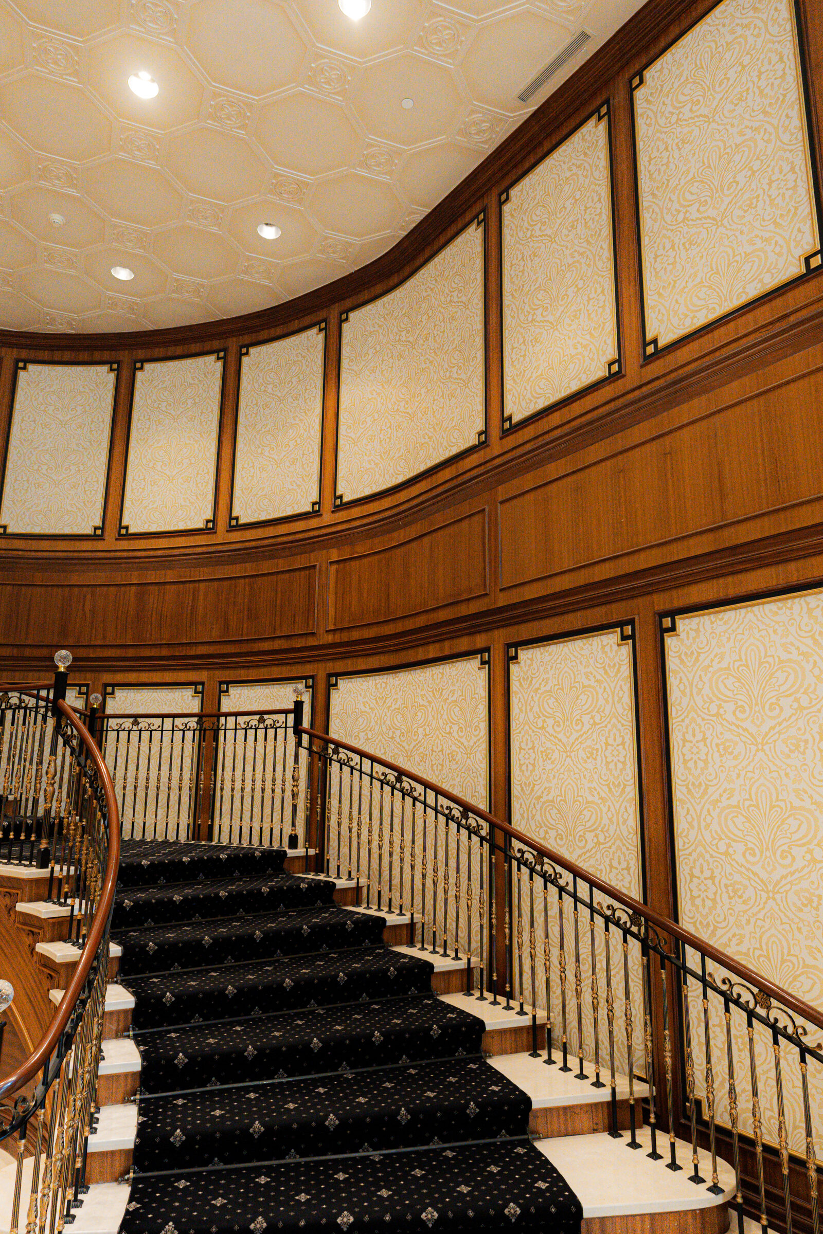 Sweeping curved staircase with an iron balustrade rising through the oval Avignon lobby