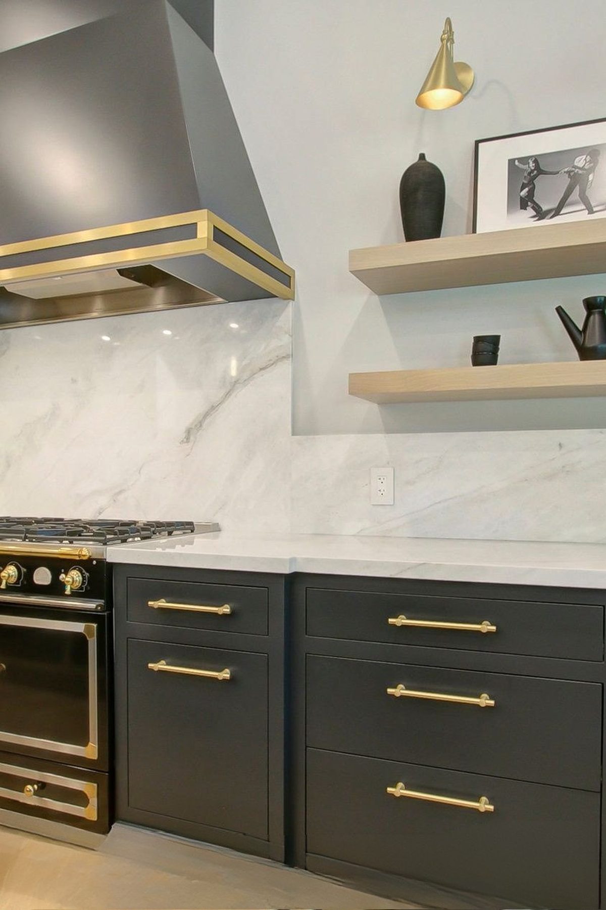Chef kitchen in charcoal cabinetry with a brass range and marble surfaces