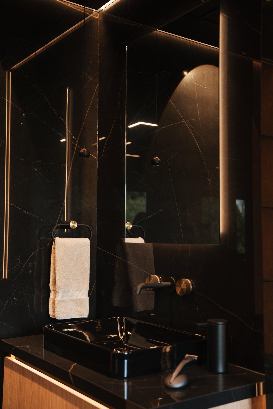 Black marble vanity with a vessel sink and a backlit oval mirror